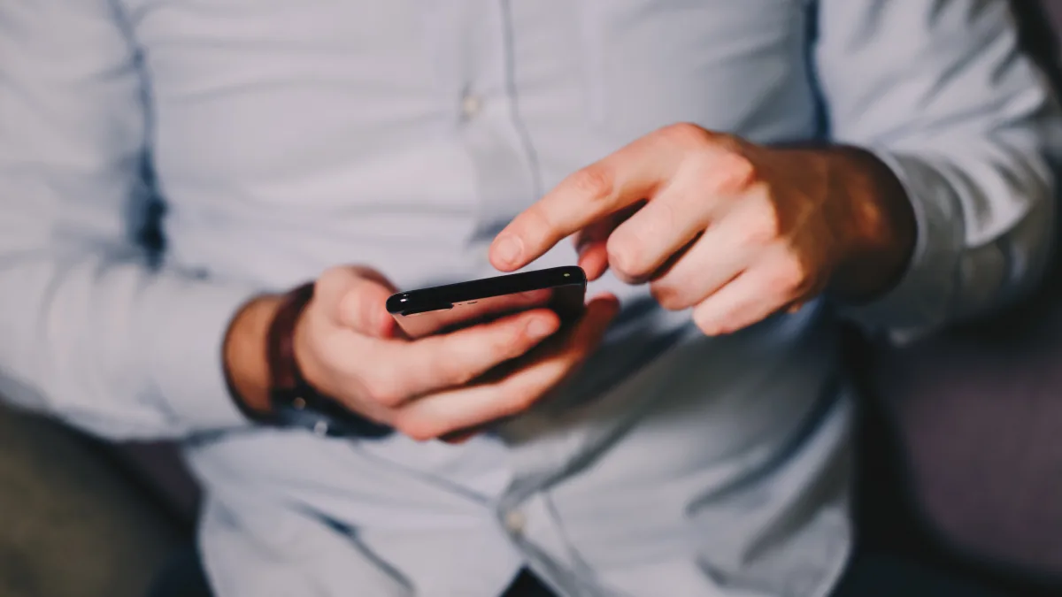 Mains tenant un smartphone pour lire un message, dans le cadre des SMS d’une association caritative