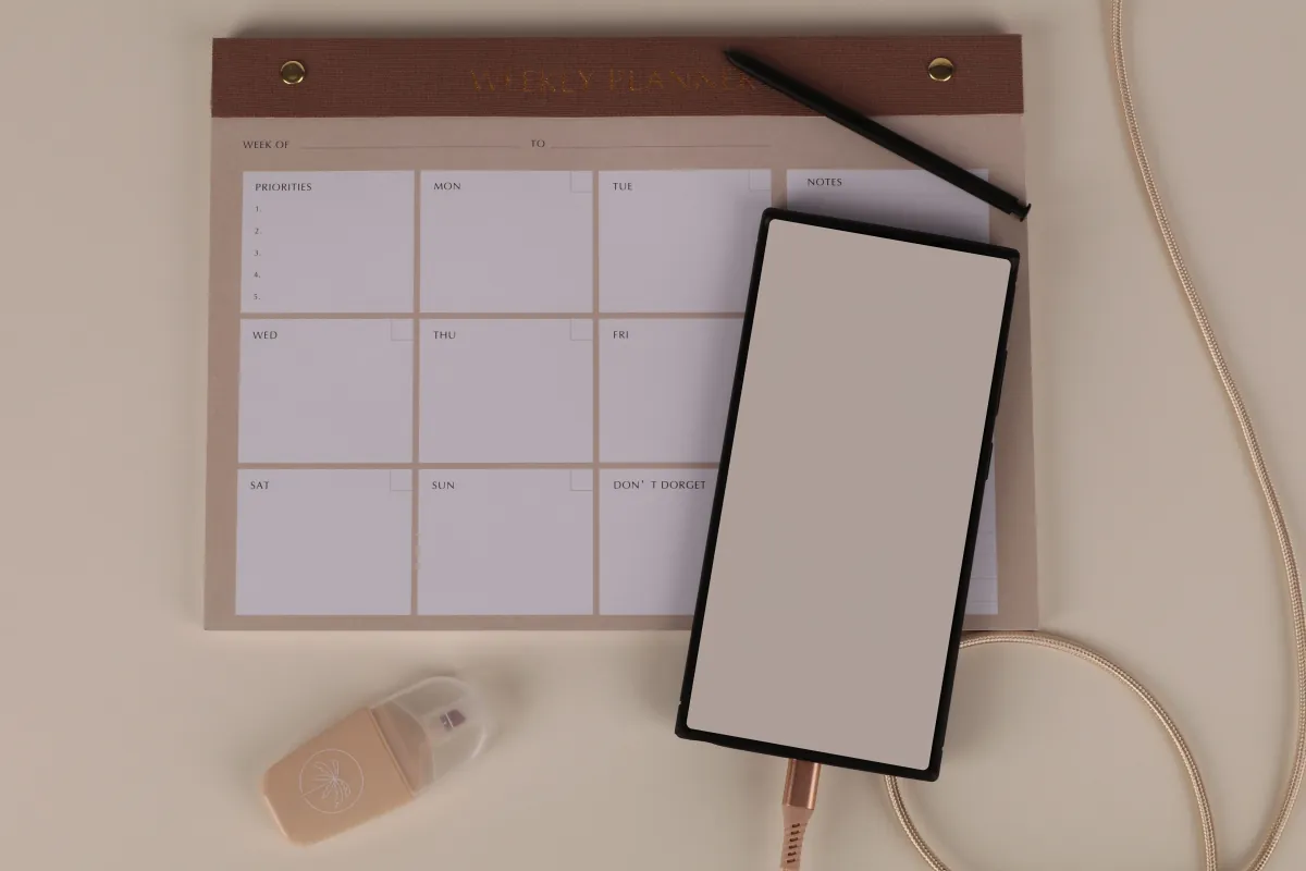 Planning hebdomadaire et smartphone posés sur un bureau pour organiser une campagne SMS Black Friday