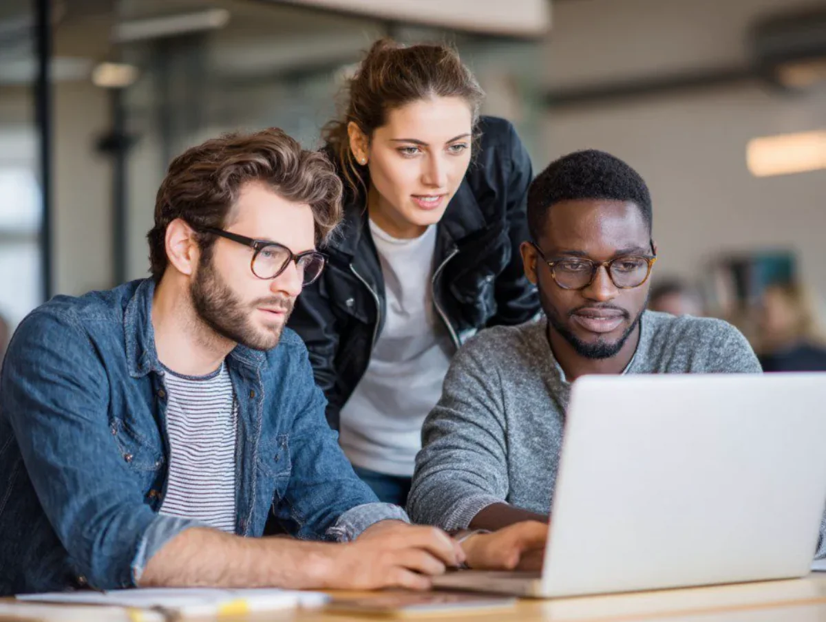 Trois collègues concentrés devant un ordinateur portable au bureau
